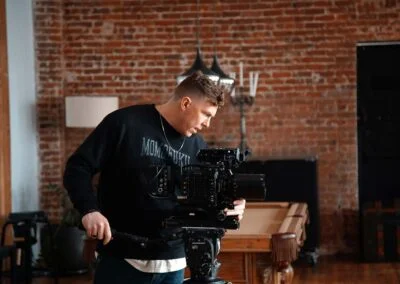 Photo of a camera inside a brick building. man looking down into the monitor of a video camera.