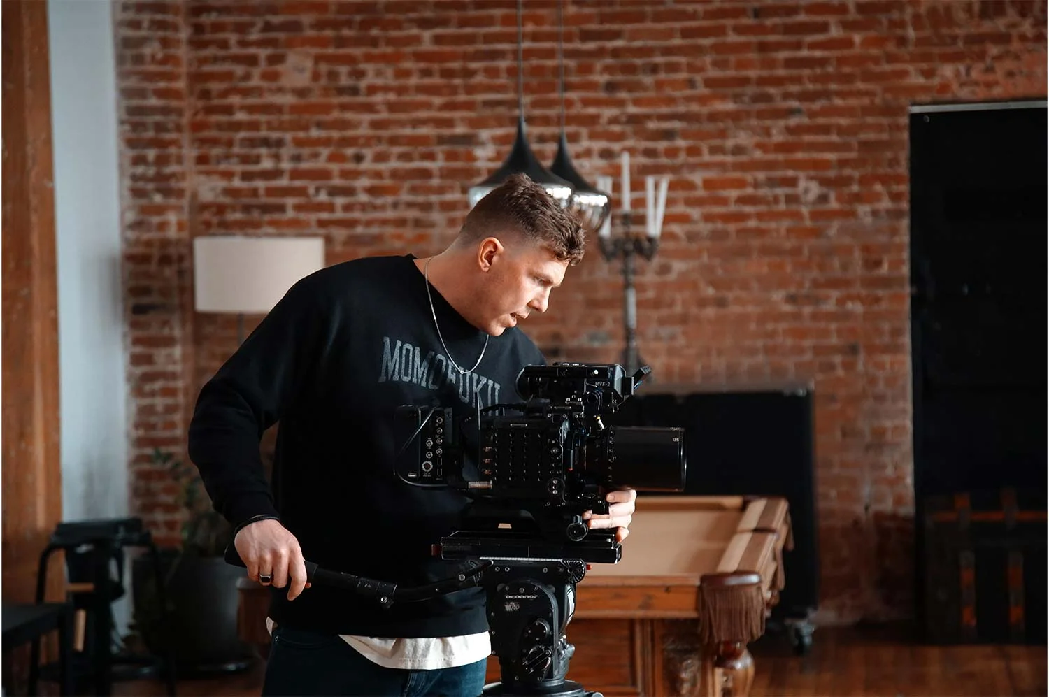 Photo of a camera inside a brick building. man looking down into the monitor of a video camera.