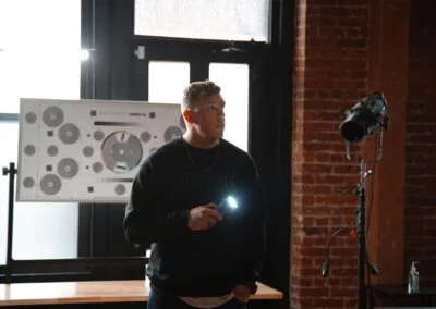 Photo of a man with a flashlight with a window behind him.