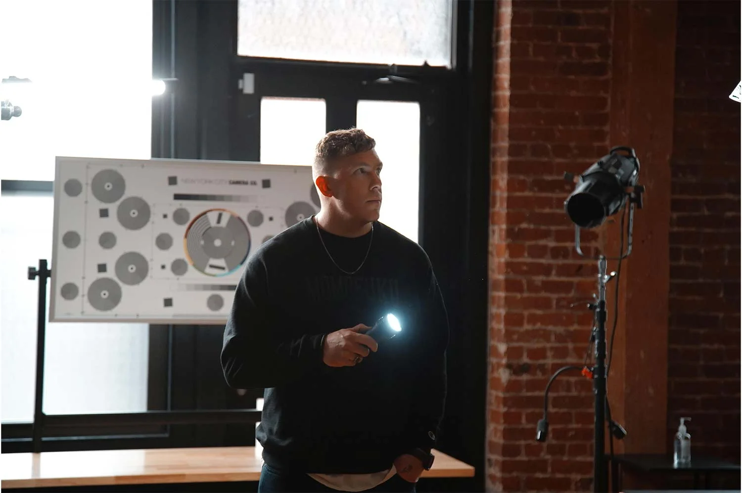 Photo of a man with a flashlight with a window behind him.